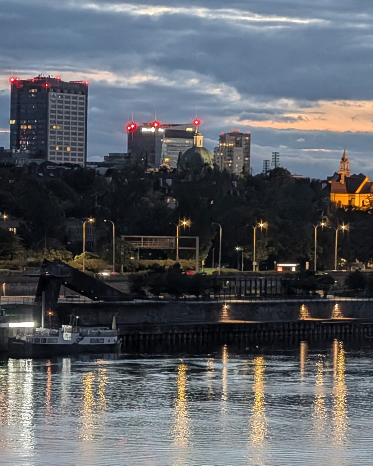 The Warsaw skyline at dusk seen across the Vistula, office towers lit against the last daylight