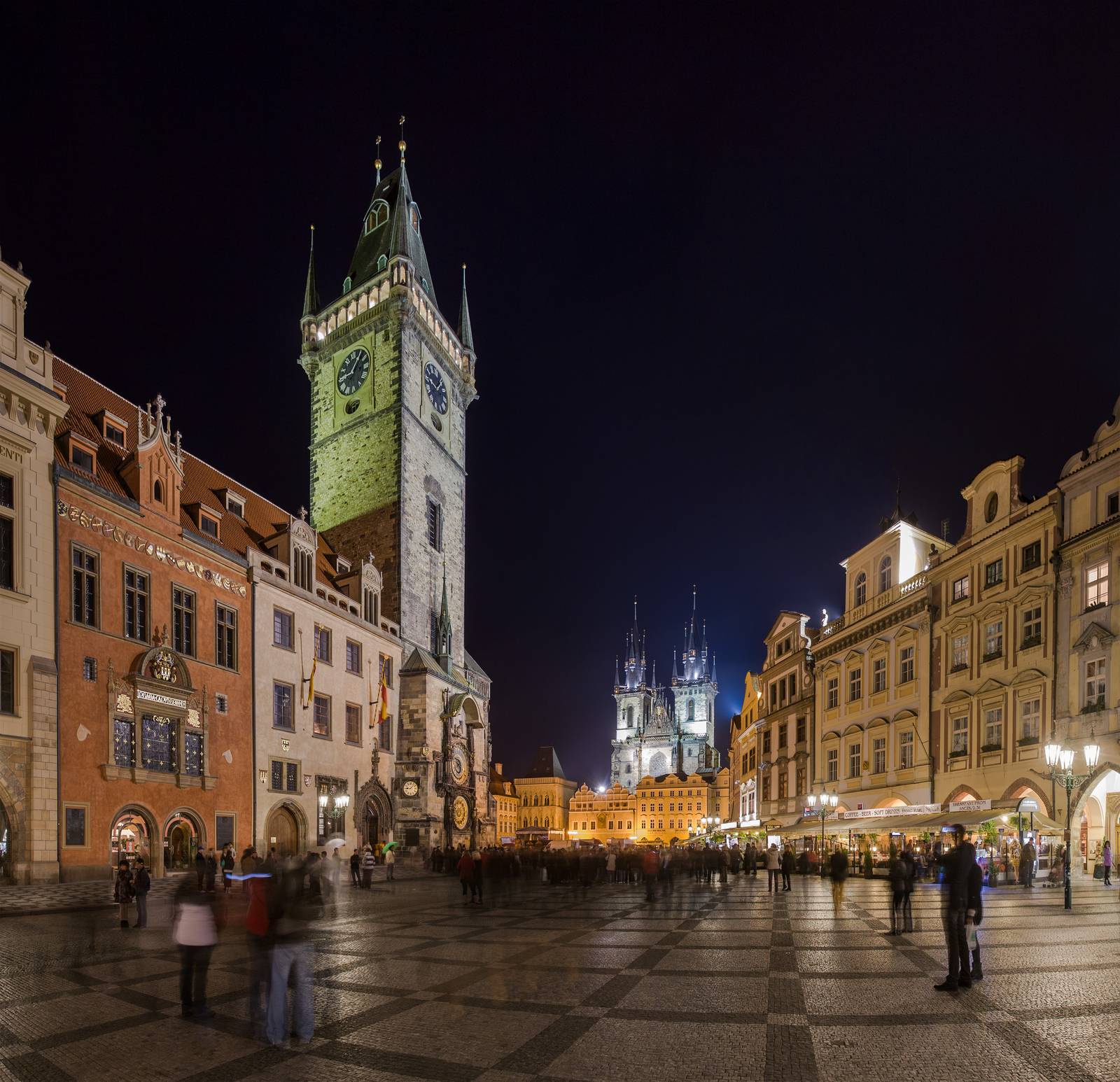 Prague Old Town Square at night with the illuminated Astronomical Clock tower and Týn Church spires visible in the background