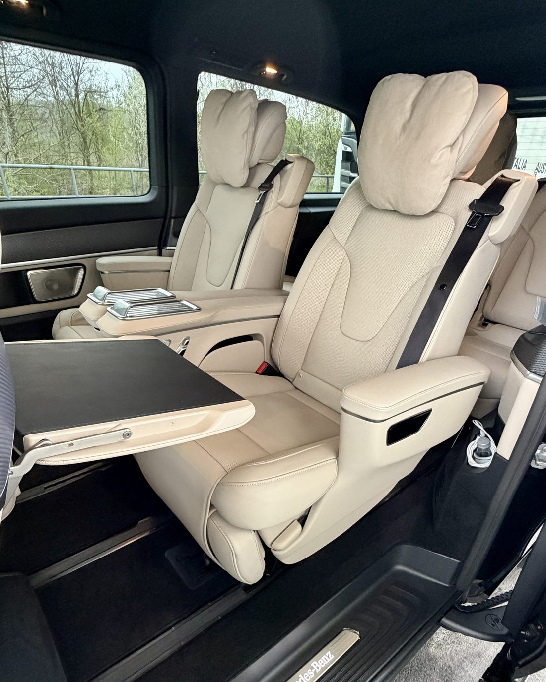 The rear cabin of a Mercedes V-Class First Class: two cream leather captain's chairs with a folding table deployed beside them