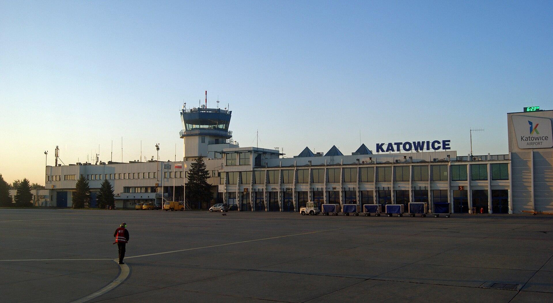 Katowice-Pyrzowice Airport terminal with the KATOWICE sign and control tower at dusk