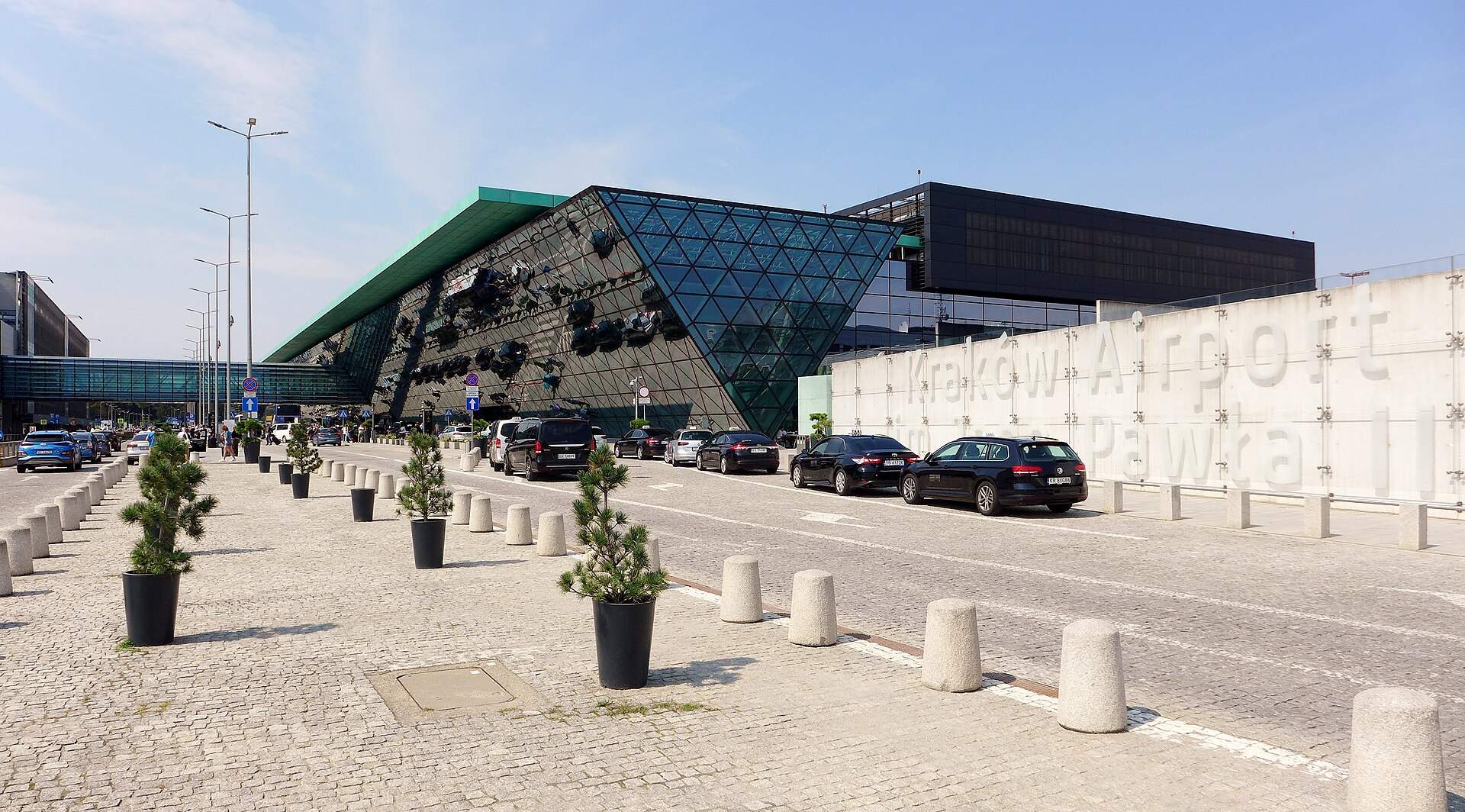 Krakow Airport terminal exterior with its triangular glass facade and Krakow Airport signage
