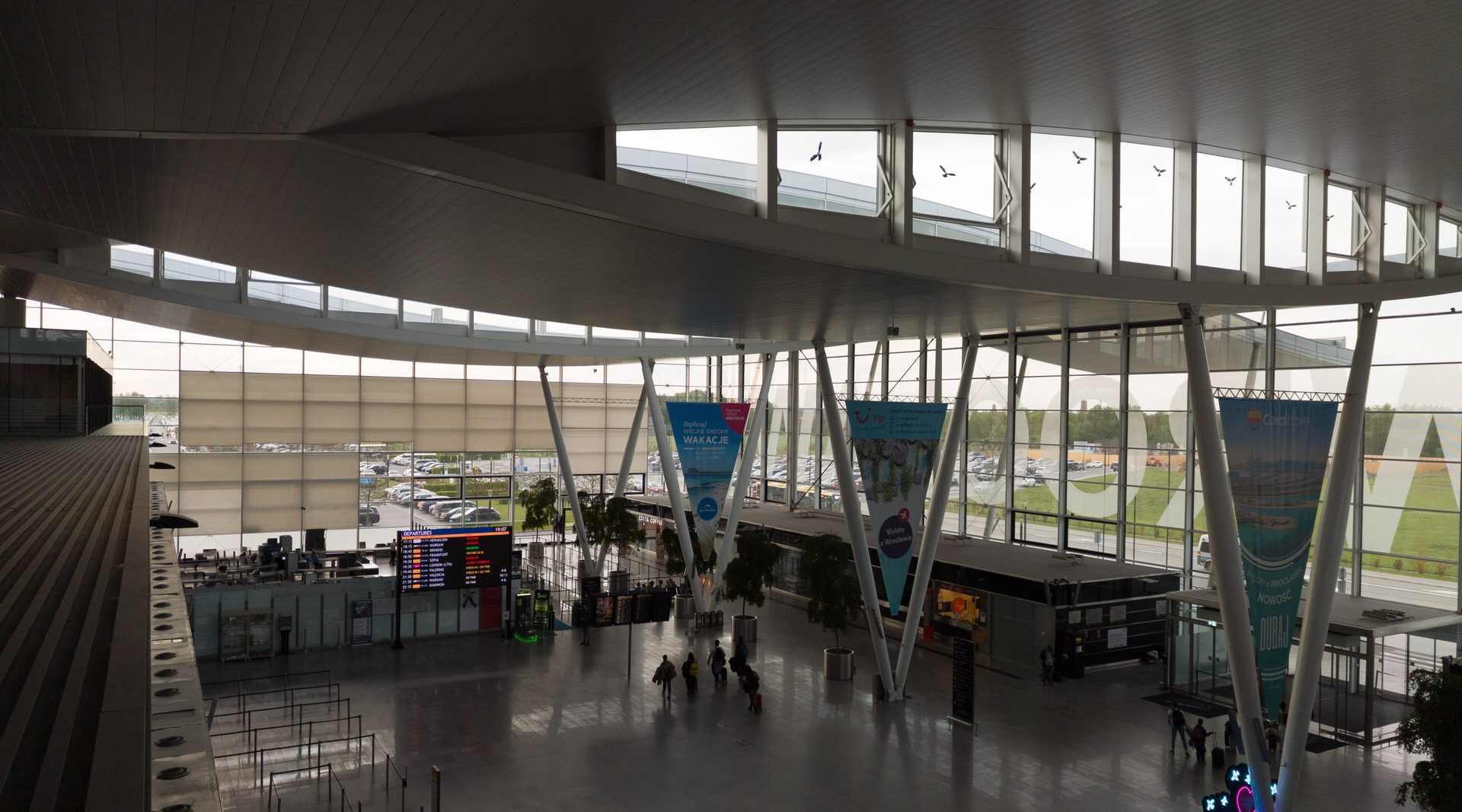 Departures hall of Copernicus Airport Wrocław under its curved roof, with the WROCŁAWIA lettering across the glazing