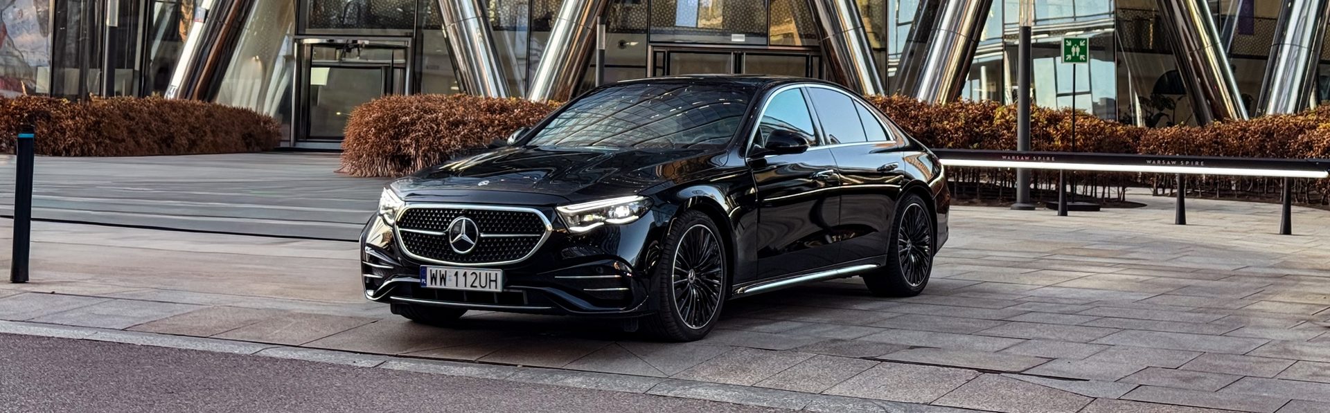 Black Mercedes-Benz E-Class in front of the Warsaw Spire towers